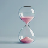 Uma ampulheta de vidro com areia rosa, sobre um fundo azul claro e minimalista, simbolizando a passagem do tempo