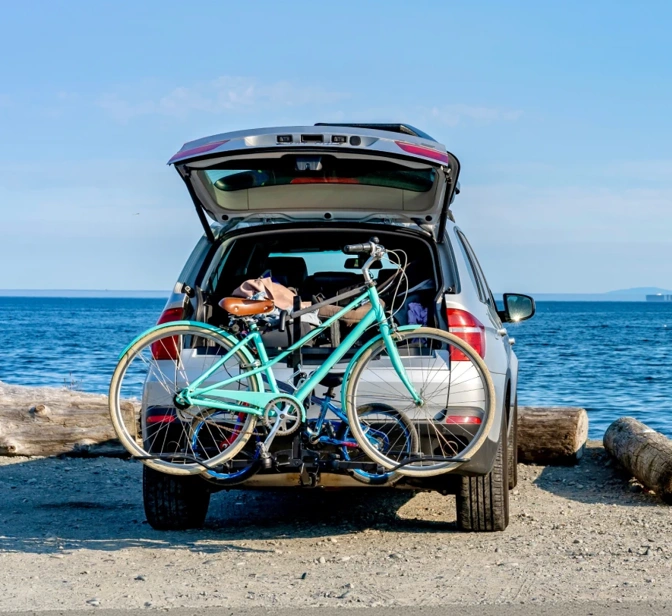 Carro com bicicleta no suporte estacionado numa praia de frente para o mar