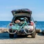 Carro com bicicleta no suporte estacionado numa praia de frente para o mar