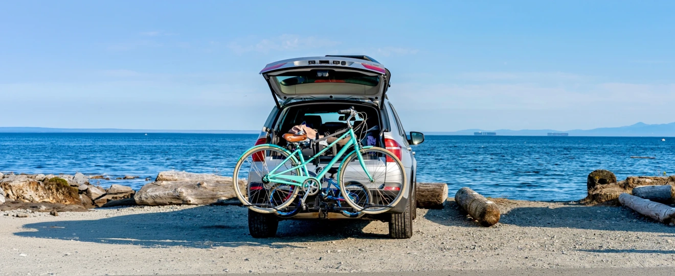 Carro com bicicleta no suporte estacionado numa praia de frente para o mar