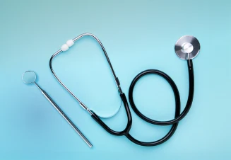 Estetoscópio e martelo de reflexos sobre fundo azul claro