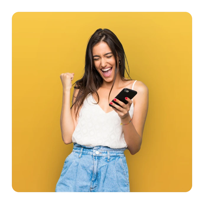 Rapariga, com um top branco e um telemóvel na mão, a celebrar