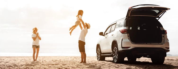man lifting his daughter in his arms, next to his new car