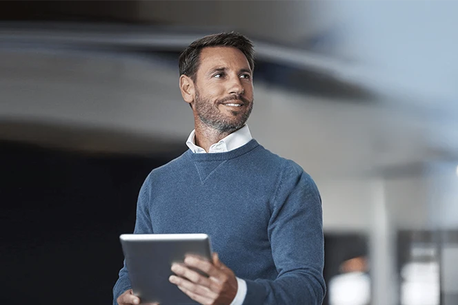 homem com camisola azul e tablet na mão