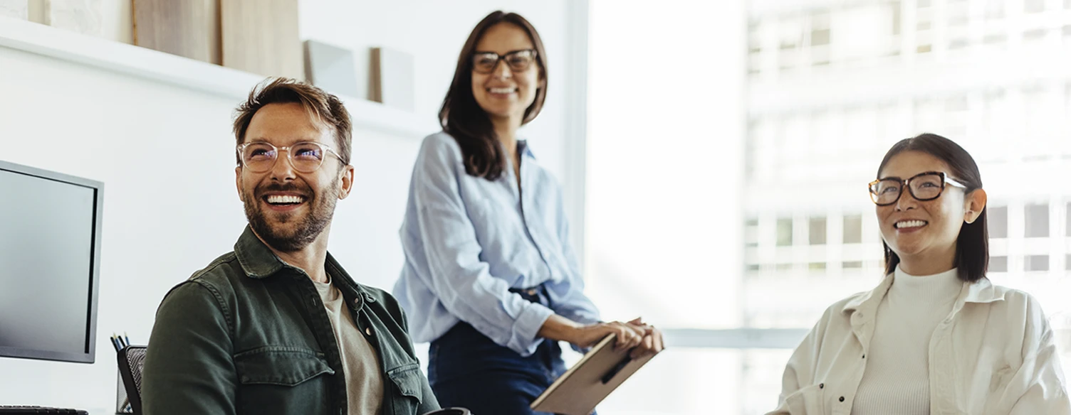 3 pessoas sorridentes numa sala de reuniões