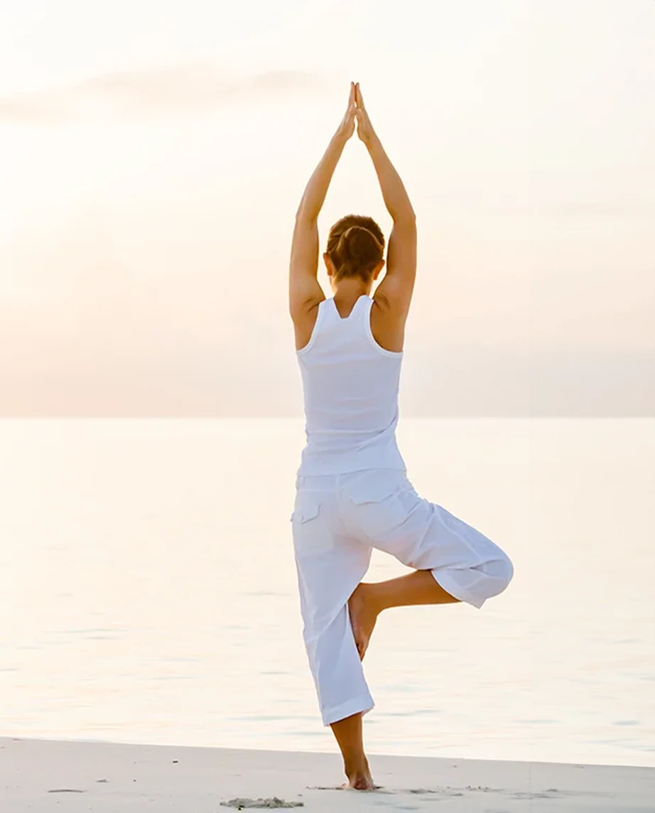 Mulher a fazer yoga na praia, ao pôr do sol