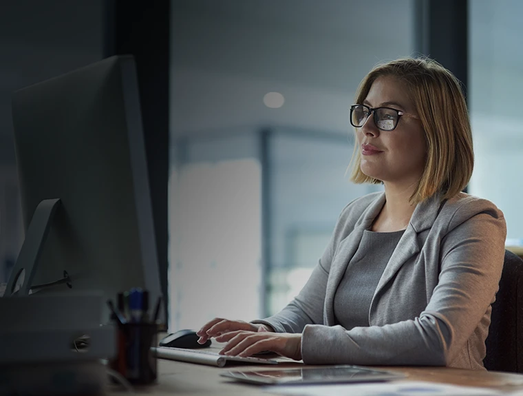 senhora sentada, a trabalhar num computador, num escritório