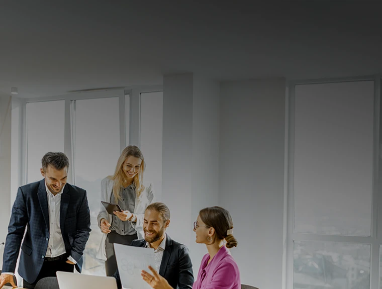 4 pessoas numa sala de reuniões, com computador e portátil, sorridentes