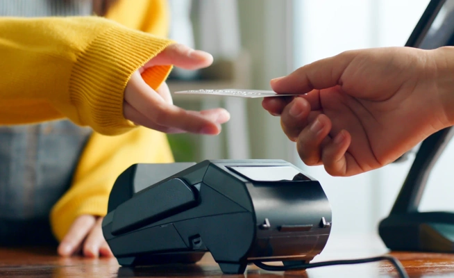 Pessoa a fazer um pagamento com cartão num terminal automático