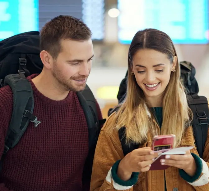 Casal de viajantes no aeroporto a olhar para um telemóvel