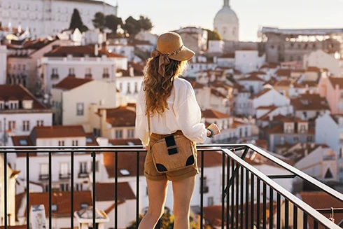 Woman in a hat on a viewpoint overlooking the rooftops of Lisbon