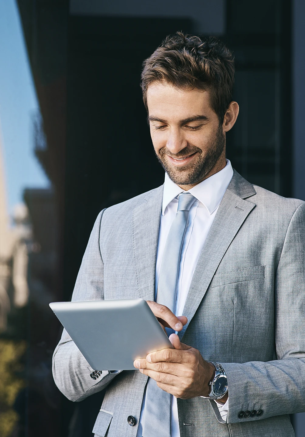 homem de fato cinzento sorridente com tablet