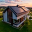 Moradia moderna com painéis solares no telhado num campo verde ao pôr do sol