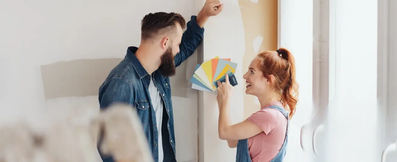 Casal a escolher cores de tinta para pintar uma parede