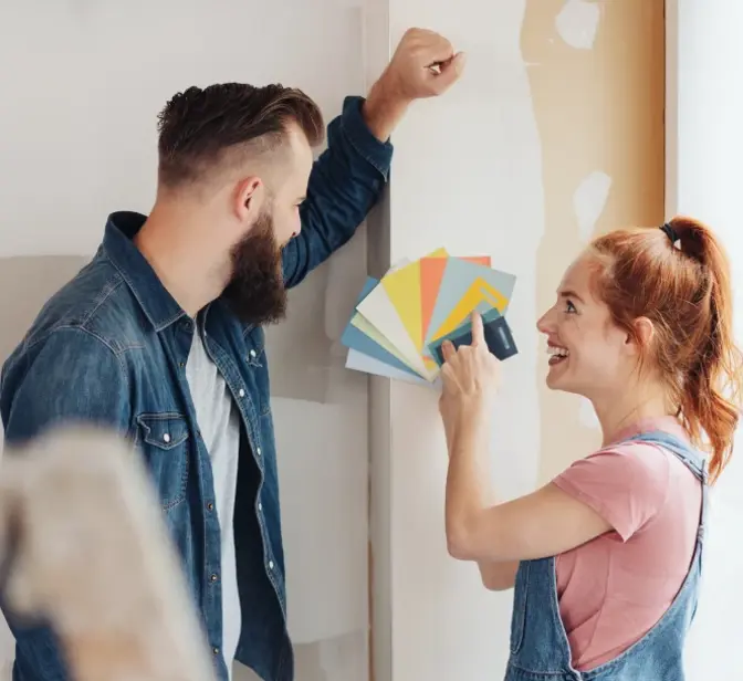 Casal a escolher cores de tinta para pintar uma parede