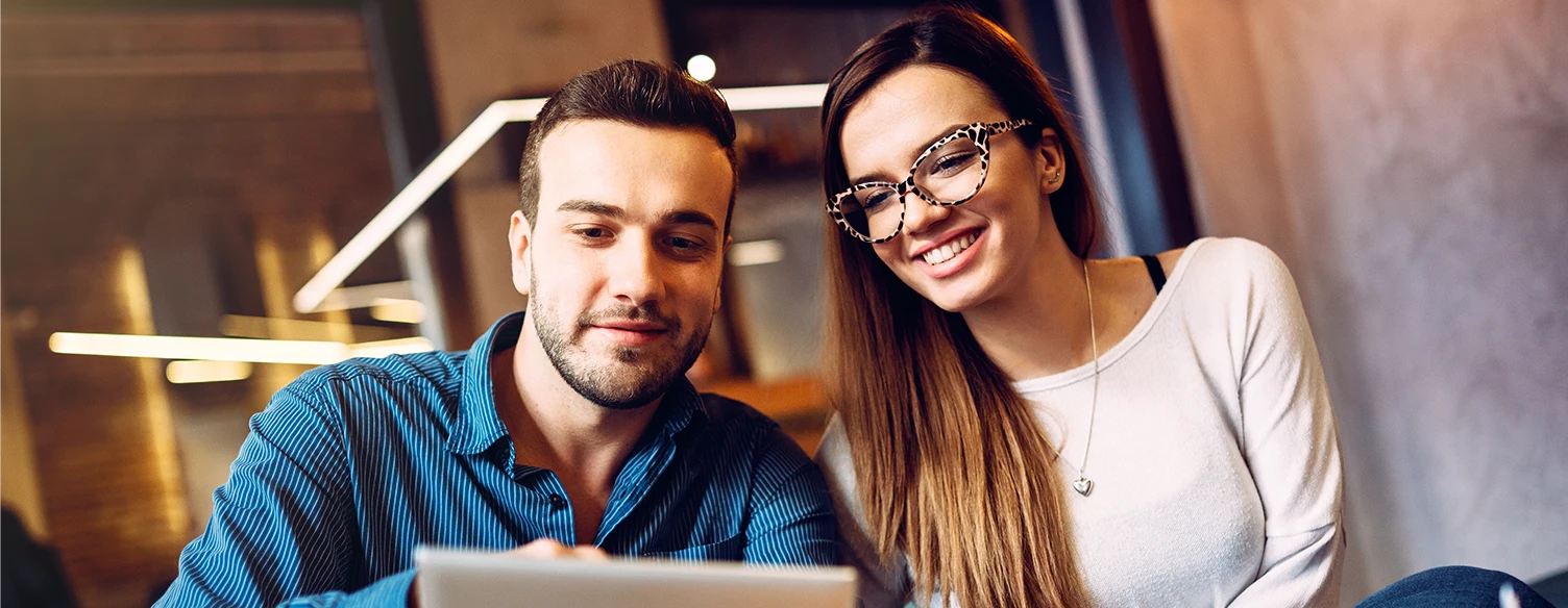 couple sitting on coffee table, holding tablet