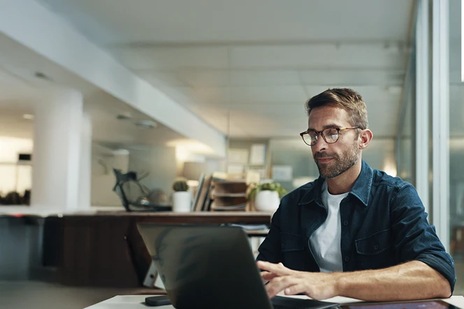 Man sitting, working on a computer, in his living room