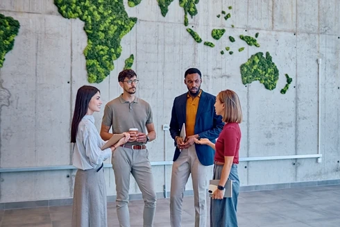 Group of colleagues talking in front of a green world map