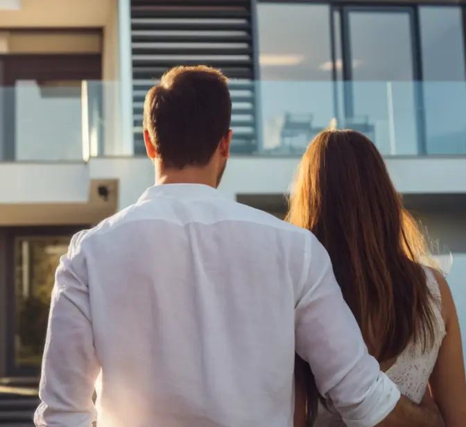 Casal de costas a observar uma casa moderna com grandes janelas