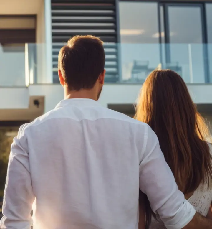 Casal de costas a observar uma casa moderna com grandes janelas