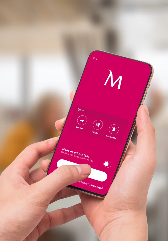 Mãos a agarrar um smartphone que apresenta o ecrã de pré-login da App Millennium