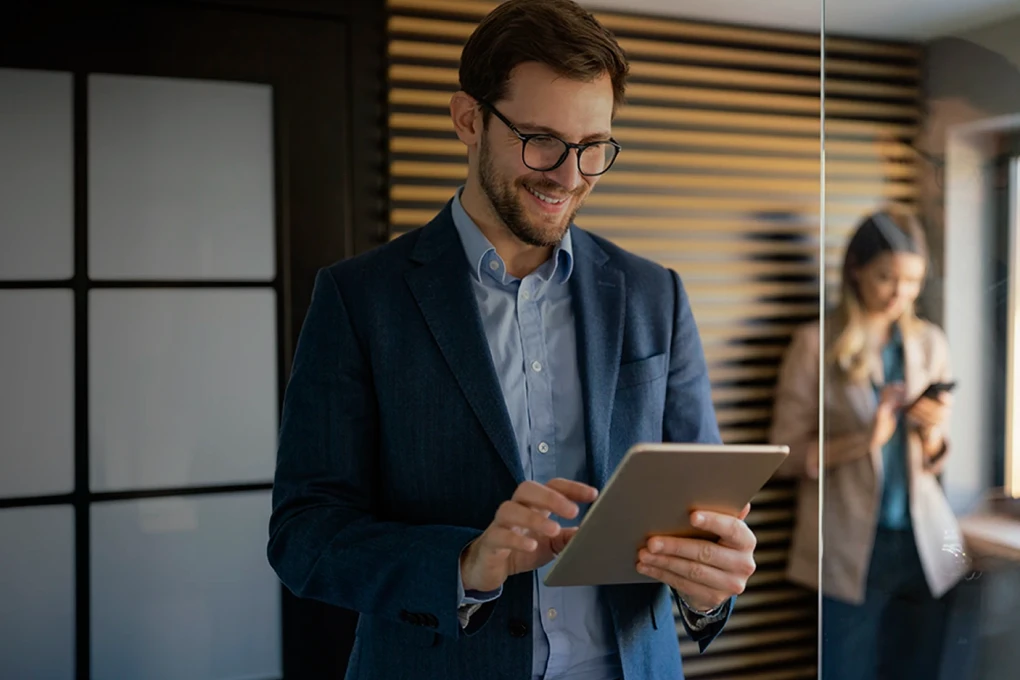 man and a woman in an office, each holding a tablet