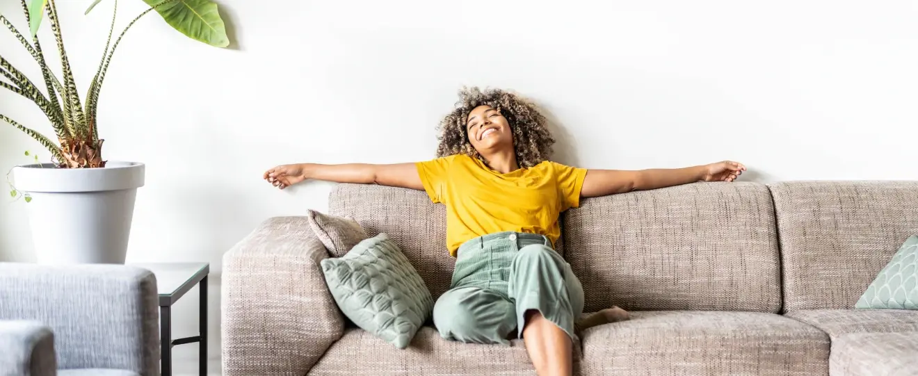 Mulher sorridente a relaxar no sofá com os braços estendidos