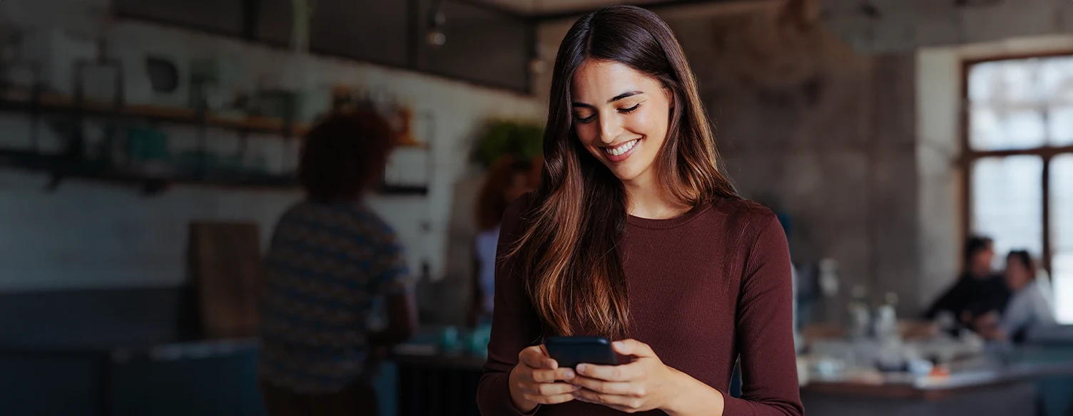 woman smilling while looking at her phone