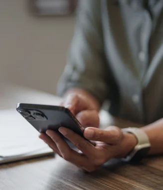 pessoa em frente a computador, a tocar no telemóvel