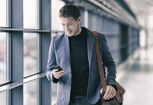 Homem a caminhar num corredor moderno enquanto utiliza o telemóvel