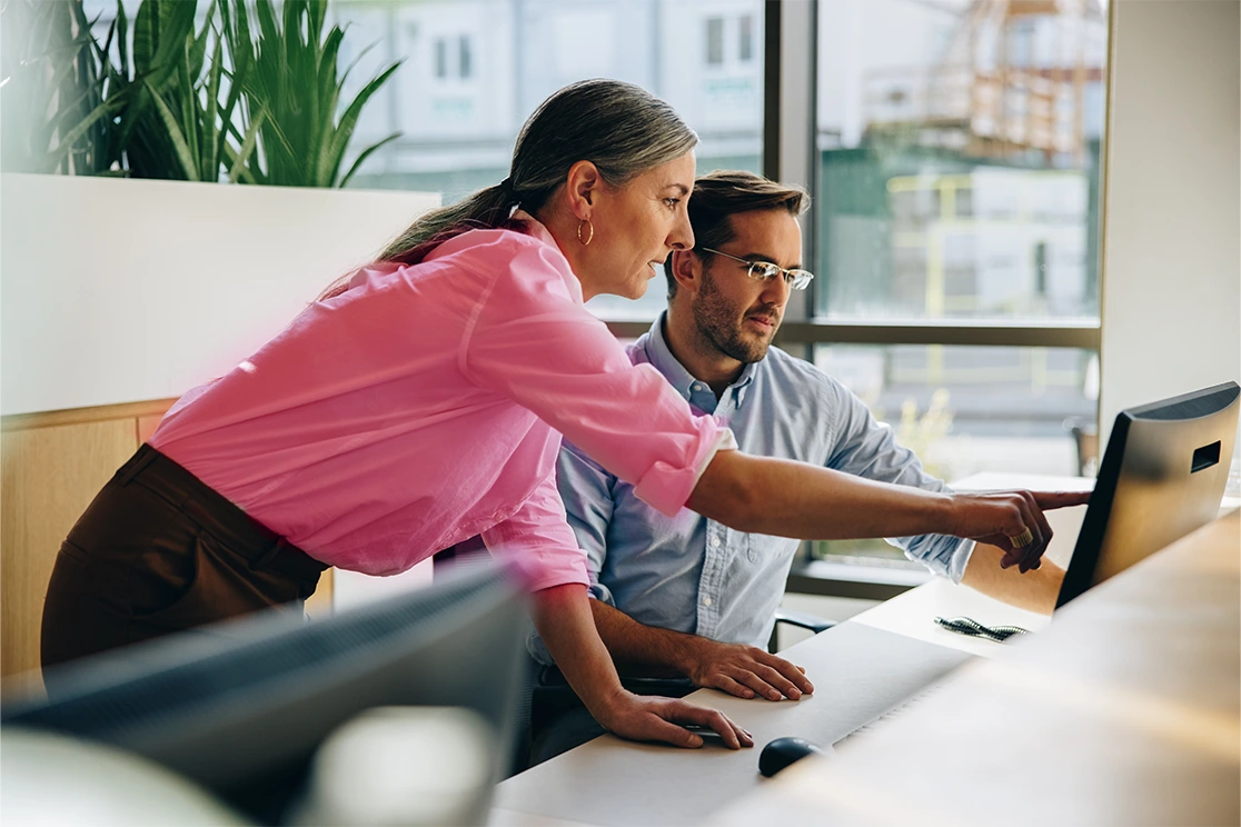 man and woman looking and pointing at pc