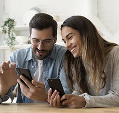 casal sorridente, mostrando telemóveis um ao outro
