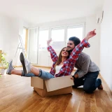 cheerful young couple in their new home, with a moving box