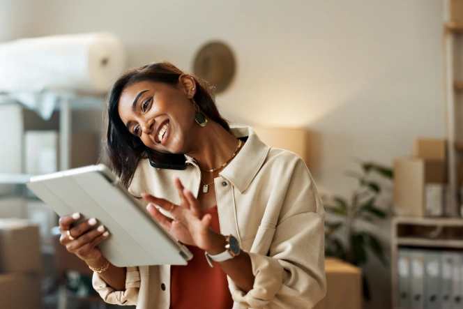 woman talking on the phone and holding a tablet in her hand, in an office