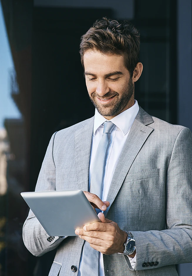 homem de fato cinzento sorridente com tablet