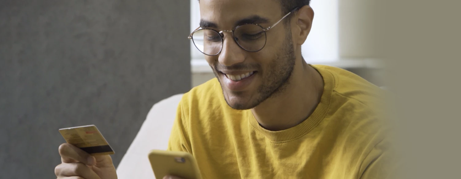 young man smilling, holding card and mobile phone