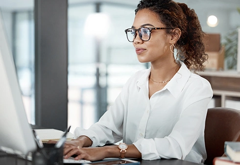 Woman with glasses working on a computer in an office environment