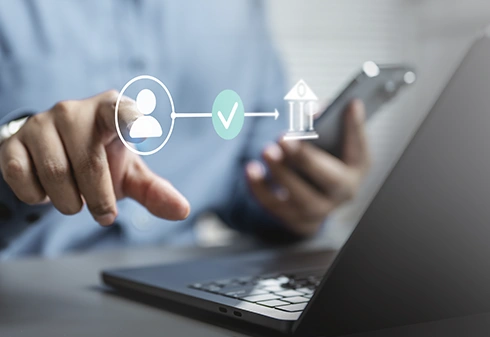 Person digitally validating identity to access the bank via mobile phone and laptop