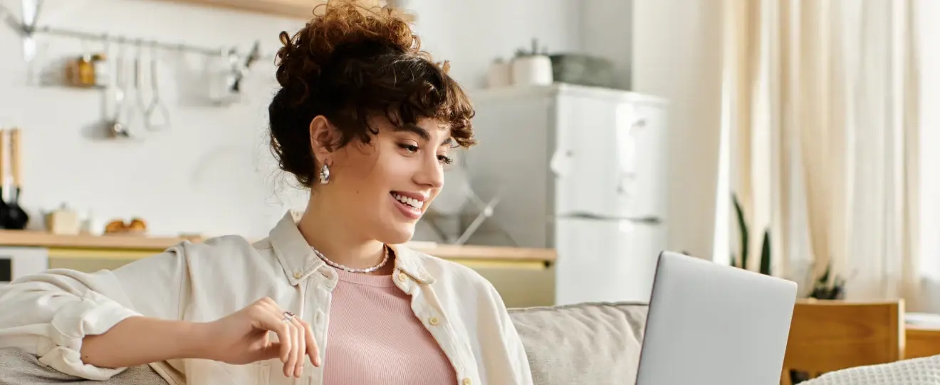 Mulher sorridente sentada no sofá a usar portátil em casa