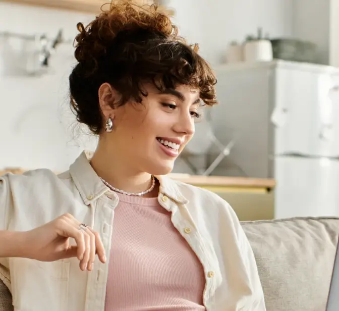 Mulher sorridente sentada no sofá a usar portátil em casa