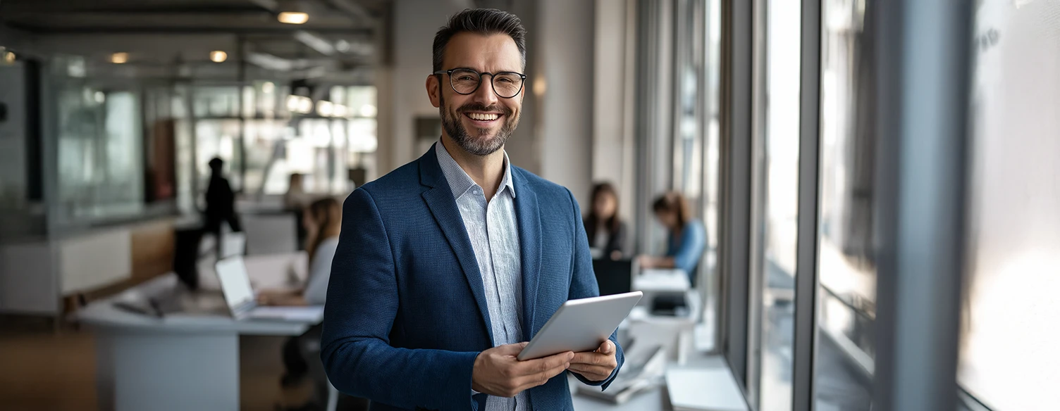 Smiling man in an office, holding a tablet
