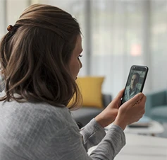 mulher sentada em casa, em videochamada no telemóvel com médico