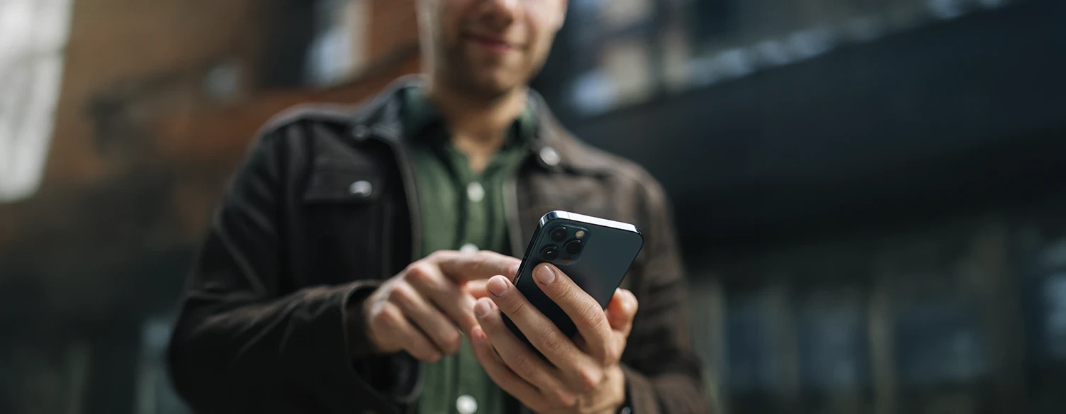 Plano próximo das mãos de um homem a utilizar um telemóvel