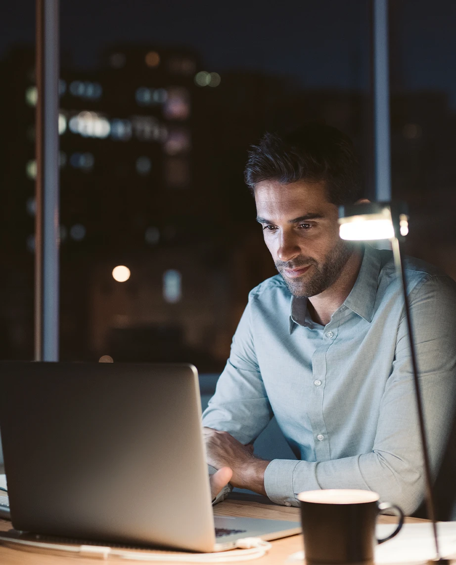 man sitting at the desk, with a laptop and a coffee cup