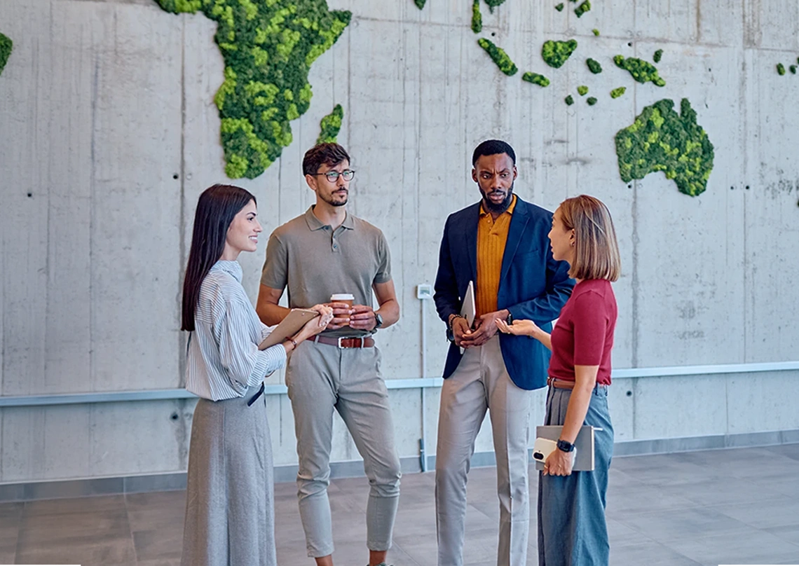 Group of colleagues talking in front of a moss world map