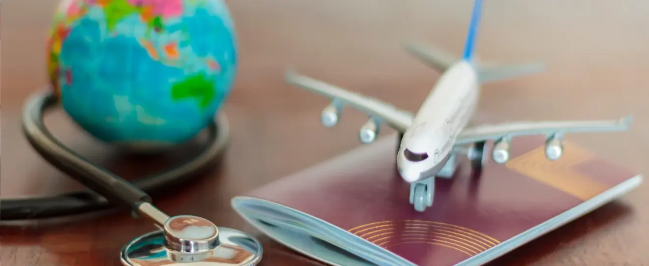 Miniatura de avião sobre passaporte, com estetoscópio e globo