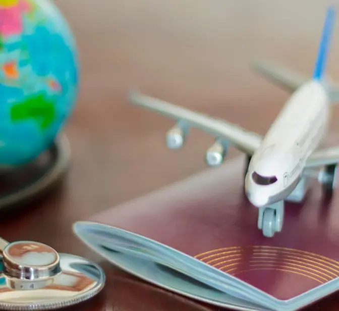 Miniatura de avião sobre passaporte, com estetoscópio e globo