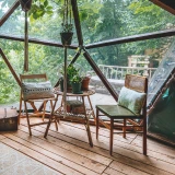 Interior de um domo geodésico com mobiliário rústico e vista para a floresta