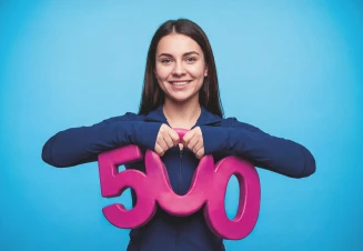 Rapariga jovem a sorrir e a pegar no numero 500