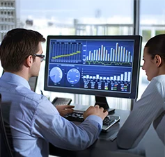 homem e mulher em frente ecrân de computador com gráficos